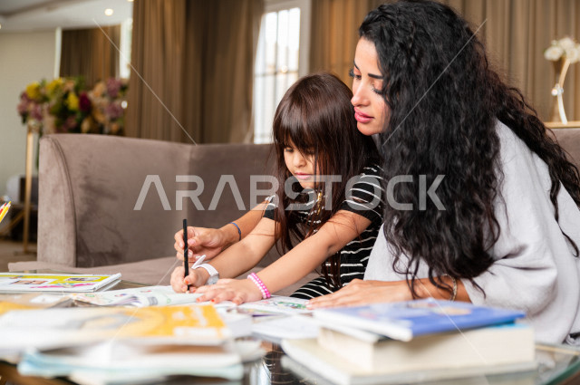 تلميذة سعودية خليجية تدرس في المنزل مع والدتها ، تساعدها على تأدية واجباتها المدرسية ، التعلم عن بعد ، مفهوم التعليم عبر الانترنت ، التعليم المنزلي اثتناء الحجر الصحي و تفشي فيروس كورونا ، العزلة الذاتية .