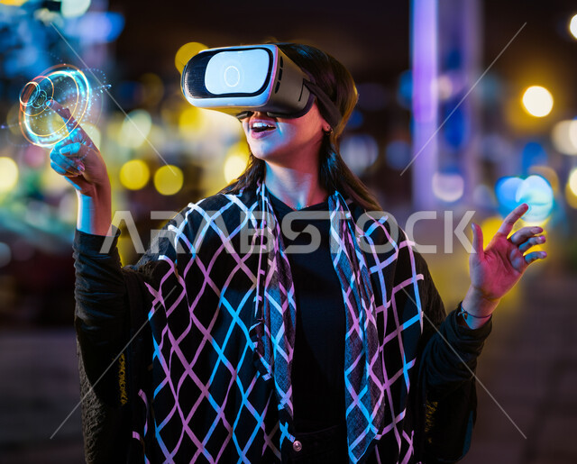 النقر ولمس عنصر هولوجرامي، فتاة عربية سعودية خليجية ترتدي نظارات الواقع الافتراضي ثلاثية الابعاد، الاستمتاع والتفاعل ومحاكاة العالم الافتراضي، ايماءات وجه تدل على الدهشة والاستغراب، حركة اصبع واشارات