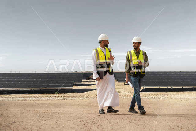حوارات ونقاشات عمل، مهندسان طاقة خليجيان عربيان سعوديان يشرفان على محطات الطاقة الشمسية في السعودية، إرتداء خوذة وسترة الحماية الخاصة بالعمل، مخططات وتصاميم هندسية، الطاقة النظيفة المتجددة، التدقيق والاشراف على العمل