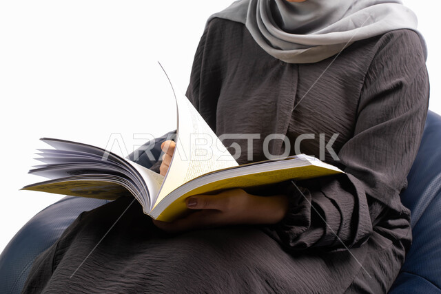إنجاز الواجبات اليومية, قضاء الوقت بالقراءة والتعلم والتثقف ، بورتريه لإمرأة عربية سعودية خليجية تجلس على كرسي مريح وتحمل بيديها كتاب  ، الاستمتاع بقراءة الكتب , ثقافة التعلم الذاتي, خلفية بيضاء