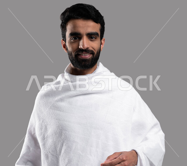 Performing Umrah in Makkah Al-Mukarramah in the holy month of Ramadan, a close-up portrait of a Saudi Arabian Gulf Muslim man wearing Ihram clothes, facial gestures indicating happiness, performing Hajj and Umrah rituals, Islamic practices and worship, gr