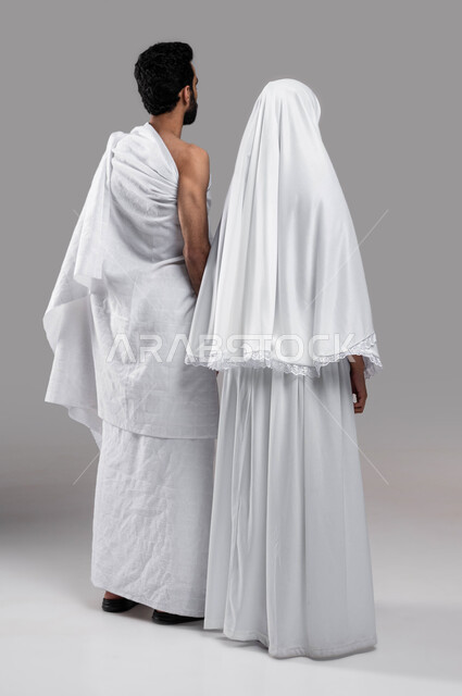 Visiting the Sacred House of God in Makkah Al-Mukarramah, the concept of intimacy between the spouses, performing Hajj and Umrah in the Hajj season 2023, a picture from the back of a Saudi Arabian Gulf couple wearing Ihram clothes, Islamic women and worsh