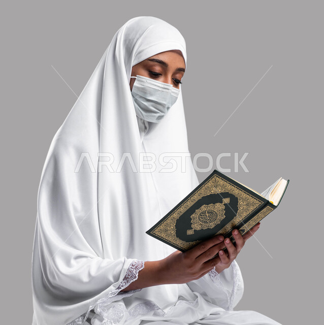 Getting closer to God by reading the Qur’an and contemplating its verses, adhering to the preventive precautions of Corona, performing the rituals of Hajj and Umrah in the 2023 season, a portrait of a Saudi Arabian Gulf woman wearing a prayer dress and a 