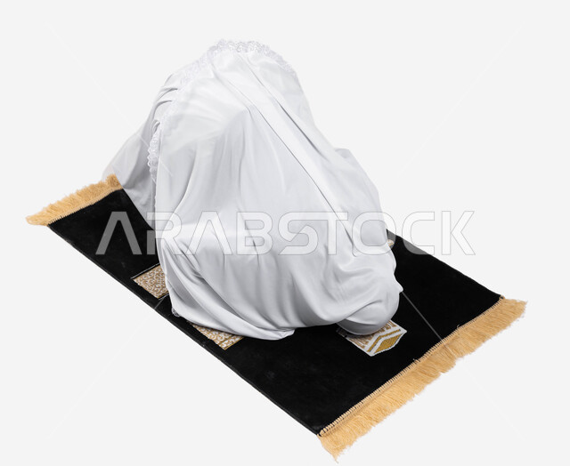 Prostration on the prayer rug, prayer and supplication to God, a portrait of a Saudi Arabian Gulf woman wearing the Ihram dress and performing the obligatory prayer, performing the rituals of Hajj and Umrah, drawing closer to God by performing acts of wor