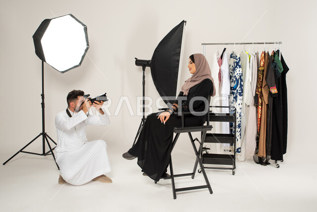 Advanced cameras and equipment, modern fashion model and models, portrait for a photo session in the studio, a Saudi Arabian Gulf photographer taking photographs of a woman sitting on a chair, Gulf women's abayas, behind the scenes, advertising marketing