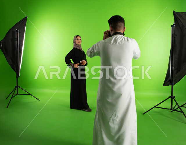 Modern fashion model and models, professional Saudi Arab Gulf photographer taking photographs of a woman wearing a Gulf women's abaya, advanced cameras and equipment, chroma for a studio photo session, marketing advertising photography, green screen backg