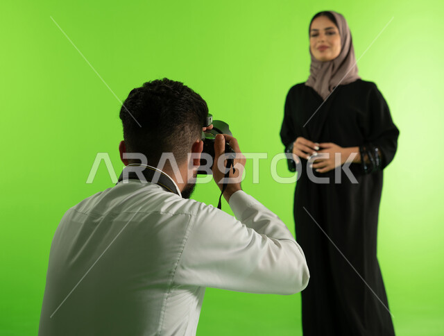 A sophisticated modern electronic camera, chroma for a photo session in the studio, a professional Saudi Arab Gulf photographer taking photographs of a woman wearing a Gulf women's abaya, advertising marketing photography, fashion model and modern models,