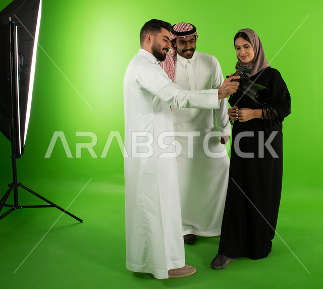 كاميرات إلكترونية متطورة، مراجعة واختيار أفضل الصور من الكاميرا، مصور عربي سعودي خليجي يقوم بانتقاء الصور الفوتوغرافية مع العارضين، كروما جلسة تصوير في الاستوديو، خلفية شاشة خضراء، خلف الكواليس