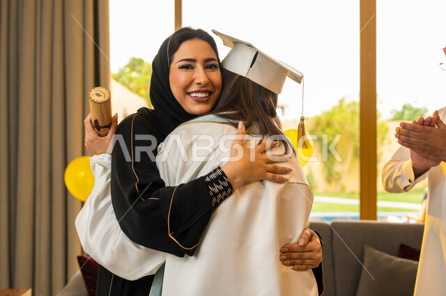خريجة جامعية ترتدي ملابس التخرج، ام تقوم بمعانقة ابنتها فرحا بتخرجها من الجامعة بتفوق وامتياز، الاحتفال بالتخرج من الجامعة، ايماءات وجه تدل على السعادة، التعليم في السعودية