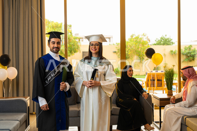 الاحتفال بالتخرج من الجامعة في احدى الشاليهات، شابة ترتدي النظارات الطبية، خريج وخريجة جامعيين يرتديان ملابس التخرج، عائلة عربية خليجية سعودية سعيدة، ايماءات وجه تدل على السعادة، التعليم في السعودية