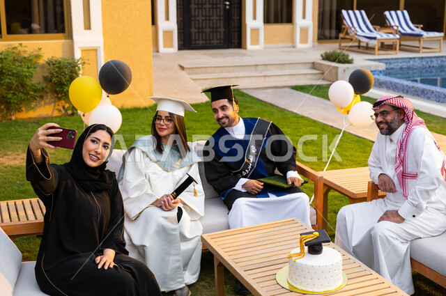 A mother is taking memorial photos through a mobile phone, a happy Saudi Gulf Arab family, university graduation celebration, male and female university graduates wearing graduation clothes and holding a certificate of success and excellence, facial gestu
