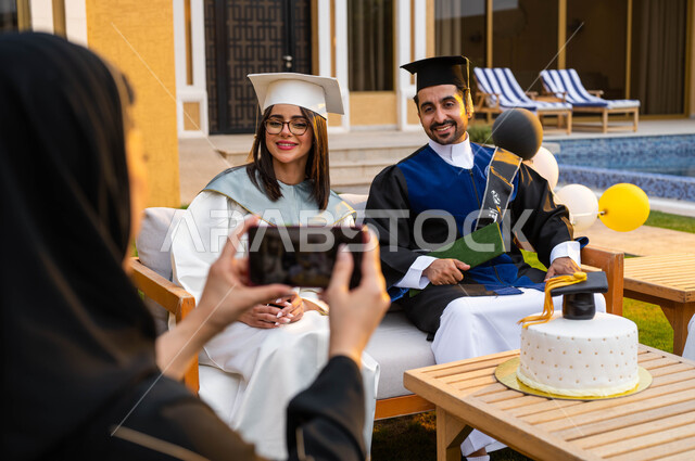 كيكة مزينة بقبعة التخرج، ام تقوم بالتقاط الصور التذكارية لابنائها من خلال الهاتف المحمول، الاحتفال بالتخرج من الجامعة، خريج وخريجة جامعيين يرتديان ملابس التخرج ويمسكان شهادة النجاح والتفوق، التعليم في السعودية