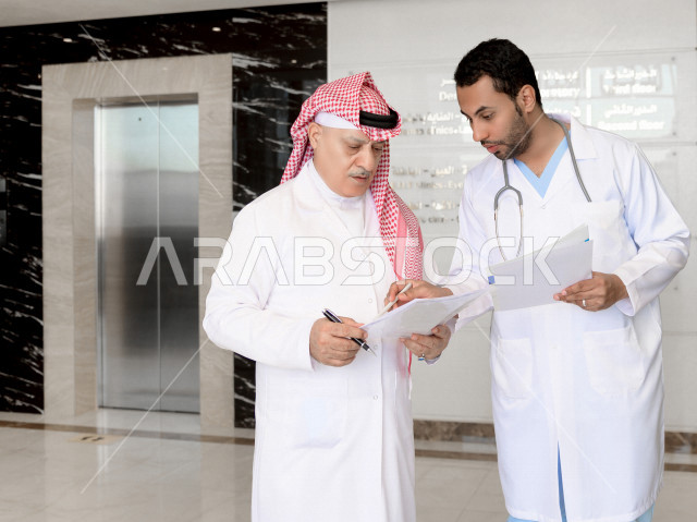 طبيبان عربيان خليجيان سعوديان يعملان داخل المستشفى ، يتبادلان الاستشارات الطبية ، مراجعة تقارير الحالات المرضية، العمل الجماعي للأطباء الاخصائيين في المستشفى ، مفهوم الطب والرعاية الصحية