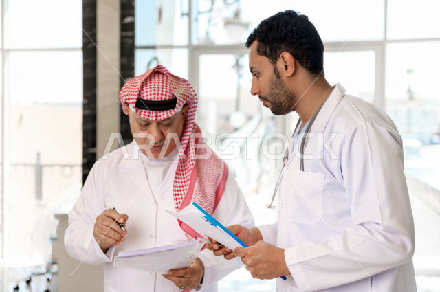 طبيبان عربيان خليجيان سعوديان يعملان داخل المستشفى ، يتبادلان الاستشارات الطبية ، مراجعة تقارير الحالات المرضية، العمل الجماعي للأطباء الاخصائيين في المستشفى ، مفهوم الطب والرعاية الصحية