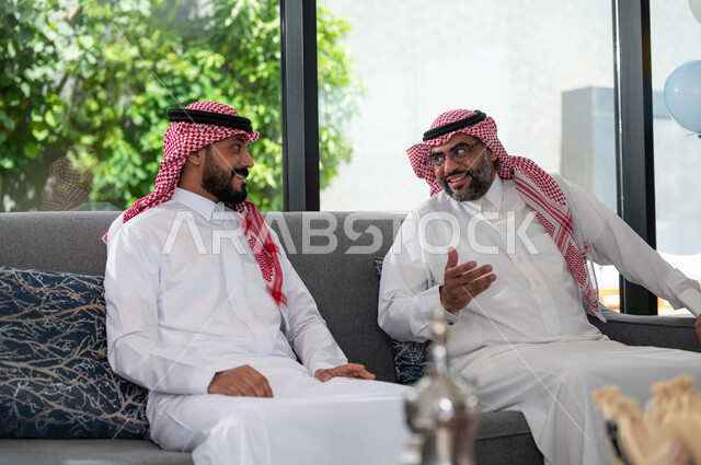 الاحتفال في عيد الاضحى المبارك مع الابناء ,رجل عربي خليجي سعودي مع والده يرتديان الثوب والشماغ السعودي, أجواء العيد في المجتمع العربي السعودي, ايماءات تدل على السعادة, تبادل الاحاديث والنقاشات, اعياد ومناسبات اسلامية