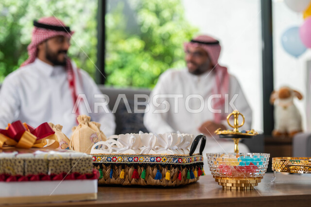 الاحتفال في عيد الاضحى المبارك مع الابناء ,ارتداء الثوب والشماغ السعودي, أجواء العيد في المجتمع العربي السعودي, ايماءات تدل على السعادة, صورة مقربة لضيافة العيد وسلة القرقيعان, اعياد ومناسبات اسلامية