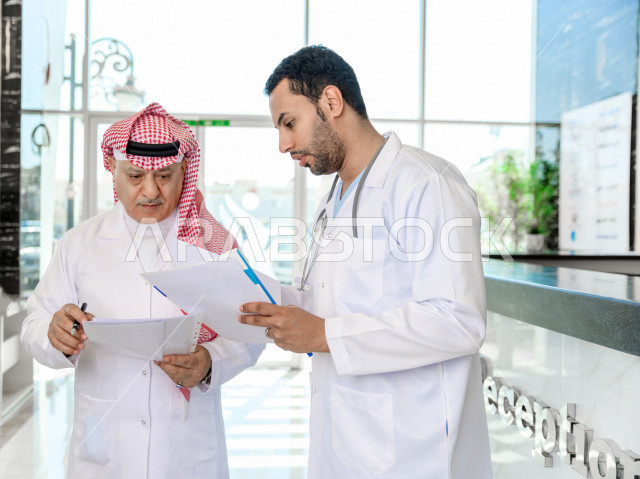طبيبان عربيان خليجيان سعوديان يعملان داخل المستشفى ، يتبادلان الاستشارات الطبية ، مراجعة تقارير الحالات المرضية، العمل الجماعي للأطباء الاخصائيين في المستشفى ، مفهوم الطب والرعاية الصحية
