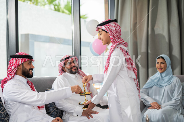 Providing Eid sweets and cakes, welcoming and honoring guests, a Saudi Arabian Gulf family celebrating Eid, gestures indicating joy and happiness, family visits and gatherings, congratulations on the advent of Eid, happy Islamic holidays and occasions.