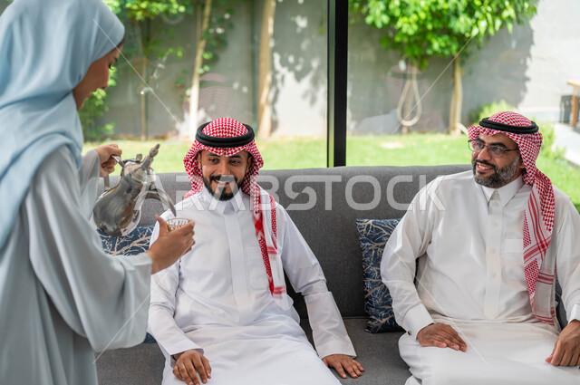 ايماءات تدل على السعاده ,حسن اكرام و استقبال الضيف, صورة مقربة لإمرأة عربيه خليجية سعودية تقوم بتقديم القهوة للضيوف, أعياد ومناسبات اسلامية, أجواء العيد في المجتمع العربي السعودي, التجمعات والزيارات الاسرية في عيد الاضحى المبارك .