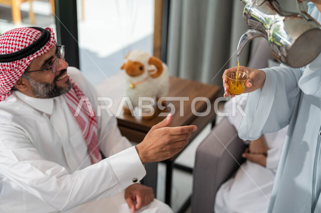 حسن استقبال و اكرام الضيف, صورة مقربة لإمرأة عربيه خليجية سعودية تقوم بتقديم القهوة للضيوف, أعياد ومناسبات اسلامية, أجواء العيد في المجتمع العربي السعودي, التجمعات والزيارات الاسرية في عيد الاضحى المبارك, ايماءات تدل على السعاده .