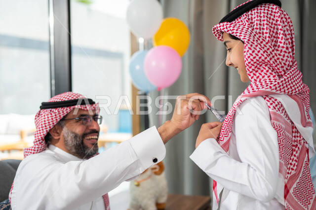 تقديم العيدية للأحفاد, أعياد ومناسبات اسلامية, أجواء العيد في المجتمع العربي السعودي,  التجمعات والزيارات الاسرية في عيد الاضحى المبارك, ايماءات تدل على السعاده , رجل مسن عربي خليجي سعودي يحتفل في العيد مع الابناء في ايام العيد السعيد في السعوديه