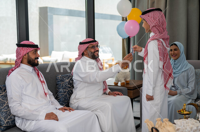 Family gatherings and visits on the blessed Eid al-Adha, presenting the Eid to the grandchildren, Islamic holidays and occasions, the atmosphere of the Eid in the Saudi Arab society, gestures indicating happiness, an elderly Saudi Arabian Gulf man celebra