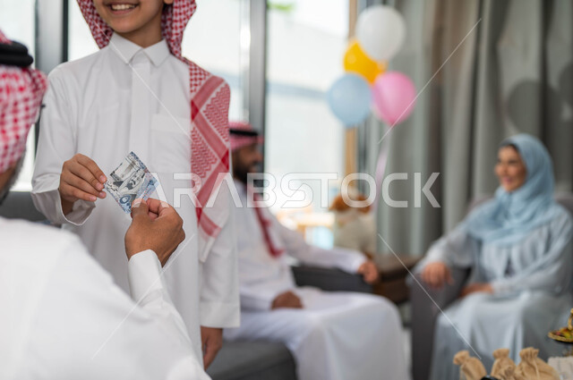 أجواء العيد في المجتمع العربي السعودي, تقديم العيدية للأحفاد, التجمعات والزيارات الاسرية في عيد الاضحى المبارك, ايماءات تدل على السعاده , رجل مسن عربي خليجي سعودي يحتفل في العيد مع الابناء في ايام العيد السعيد في السعوديه, أعياد ومناسبات اسلامية