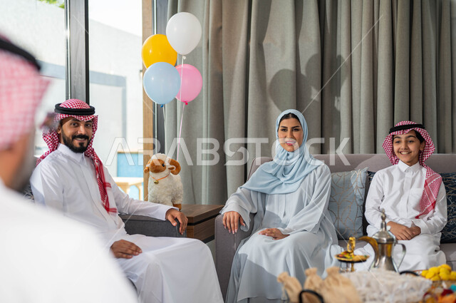 الحوارات و النقاشات بين أفراد العائلة, ايماءات تدل على الفرح والسعادة, تجمع عائلي لعائلة عربيه خليجية سعودية تحتفل بعيد الاضحى المبارك في غرفة المعيشة ,قضاء اوقات ممتعة مع الابناء, أعياد ومناسبات اسلامية .
