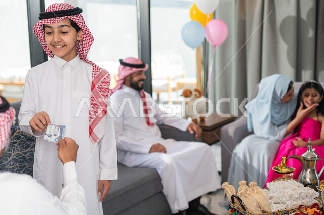 أجواء العيد في المجتمع العربي السعودي, تقديم العيدية للأحفاد, التجمعات والزيارات الاسرية في عيد الاضحى المبارك, ايماءات تدل على السعاده , رجل مسن عربي خليجي سعودي يحتفل في العيد مع الابناء في ايام العيد السعيد في السعوديه, أعياد ومناسبات اسلامية