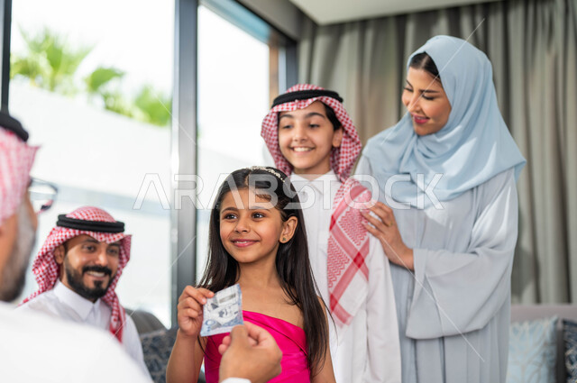 بهجة وفرحة العيد, تقديم العيدية للأحفاد, التجمعات والزيارات الاسرية, ايماءات تدل على السعاده , رجل مسن عربي خليجي سعودي يحتفل في العيد مع الابناء  في ايام العيد السعيد في السعوديه, أعياد ومناسبات اسلامية