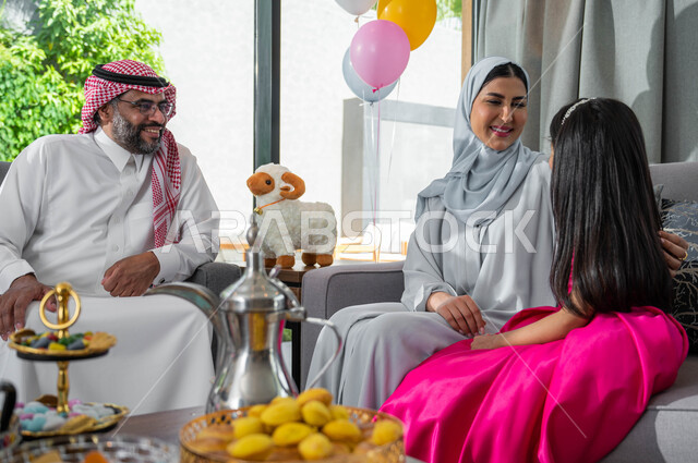 Gestures indicating happiness and joy, a close-up of a Saudi Gulf Arab family sitting in the living room and celebrating Eid al-Adha, spending fun times with children, Islamic holidays and occasions, decorations and decorations for the happy Eid.