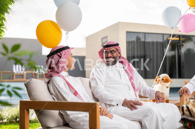 الدردشة والمحادثات بين افراد العائلة, صورة مقربة لفتى عربي خليجي سعودي مع جده يحتفلون في عيد الاضحى المبارك, ارتداء الثوب و الشماغ السعودي,  قضاء اوقات ممتعة في احدى الشاليهات الفاخره ،اعياد ومناسبات اسلامية