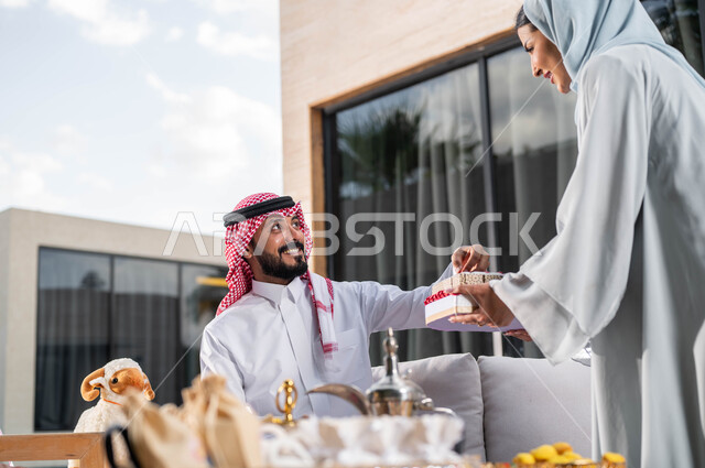 Presenting chocolate pieces on Eid Al-Adha, a veiled Saudi Arab Gulf wife, welcoming and honoring guests, spending good times in one of the luxurious chalets, family meeting and celebrating the happy Eid, Islamic holidays and events