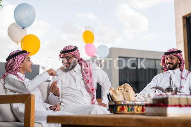 تقديم العيديه للأطفال , رجل كبير السن عربي خليجي سعودي يحتفل في العيد مع الابناء و الاحفاد في الشاليهات والمنتجعات في ايام العيد السعيد في السعوديه, التجمعات والزيارات الاسرية, أعياد ومناسبات اسلامية, ايماءات تدل على السعاده ,