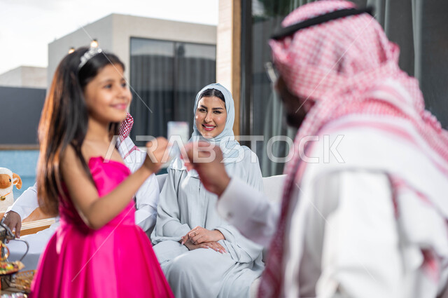 تقديم العيدية للأطفال , ايماءات تدل على السعاده , رجل مسن عربي خليجي سعودي يحتفل في العيد  مع الابناء و الاحفاد  في الشاليهات والمنتجعات في ايام العيد السعيد في السعوديه, التجمعات والزيارات الاسرية,  أعياد ومناسبات اسلامية