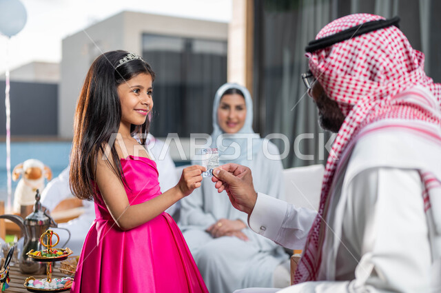 التجمعات والزيارات الاسرية, ايماءات تدل على السعاده , رجل مسن عربي خليجي سعودي يحتفل في العيد  مع الابناء و الاحفاد  في الشاليهات والمنتجعات في ايام العيد السعيد في السعوديه, أعياد ومناسبات اسلامية, تقديم العيدية للأطفال