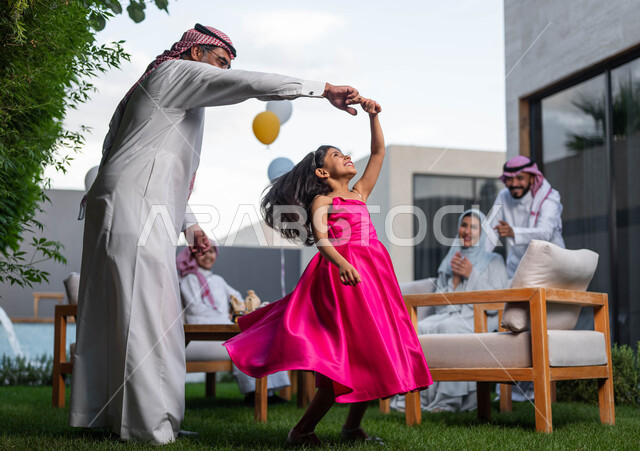 اجتماع العائله والاحتفال مع الأطفال في العيد السعيد ،رجل كبير السن عربي خليجي سعودي يرتدي الزي التقليدي السعودي يقوم باللعب مع حفيدته في احدى الشاليهات الفاخره ، انشطه ترفيهيه في الاعياد  والمناسبات العائليه