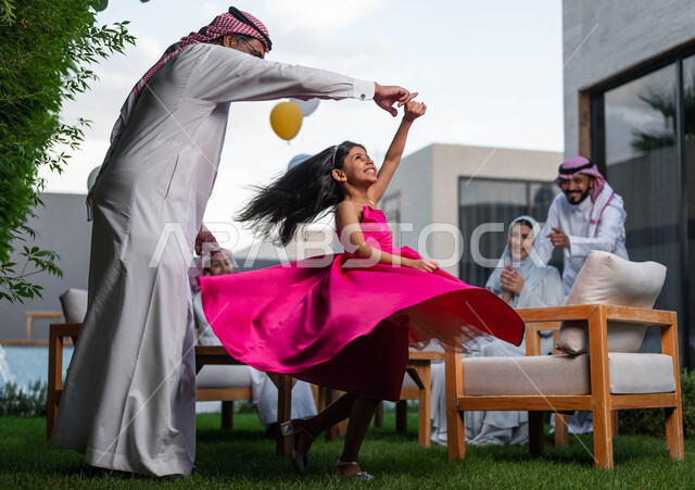 اجتماع العائله والاحتفال مع الأطفال في العيد السعيد ،رجل كبير السن عربي خليجي سعودي يرتدي الزي التقليدي السعودي يقوم باللعب مع حفيدته في احدى الشاليهات الفاخره ، انشطه ترفيهيه في الاعياد  والمناسبات العائليه