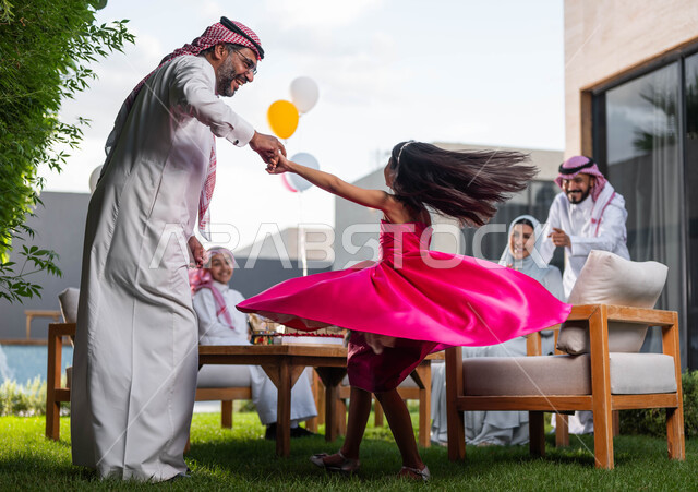انشطه ترفيهيه في الاعياد  والمناسبات العائليه, رجل كبير السن عربي خليجي سعودي يرتدي الزي التقليدي السعودي يقوم باللعب مع حفيدته في احدى الشاليهات الفاخره ، اجتماع العائله والاحتفال مع الأطفال في العيد السعيد 