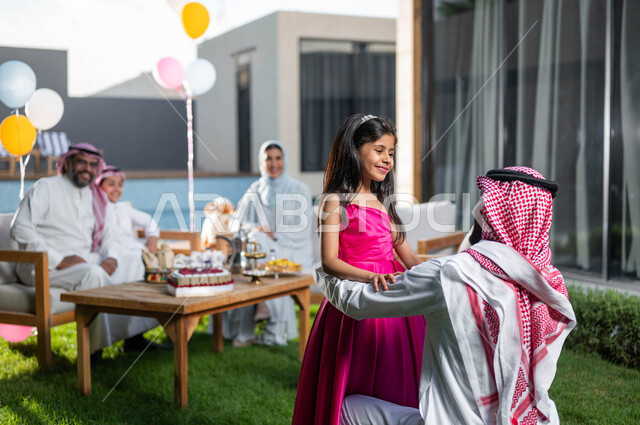 Gestures indicating happiness and joy, spending pleasant times with children in chalets and resorts during the happy Eid days in Saudi Arabia, family visits and gatherings, a Saudi Arabian Gulf father with his daughter celebrating Eid al-Adha, Islamic occ