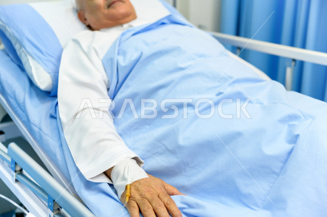 رجل كبير بالسن عربي خليجي سعودي مريض مستلقي على سرير المستشفى، تلقى العلاج و العناية في المستشفى ،اجراء عمليه جراحية ، مستشفى خاص بكبار السن، مفهوم الطب والرعاية الصحية