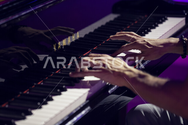 العزف على البيانو في موسم تنوين للأنشطة الترفيهية و الثقافية و التعليمية، صورة مقربة لايدي شاب سعودي يعزف على آلة البيانو الموسيقية,  العزف و الانشطة الترفيهية في مركز الملك عبد العزيز الثقافي العالمي في مدينة الظهران في المملكة العربية السعودية.