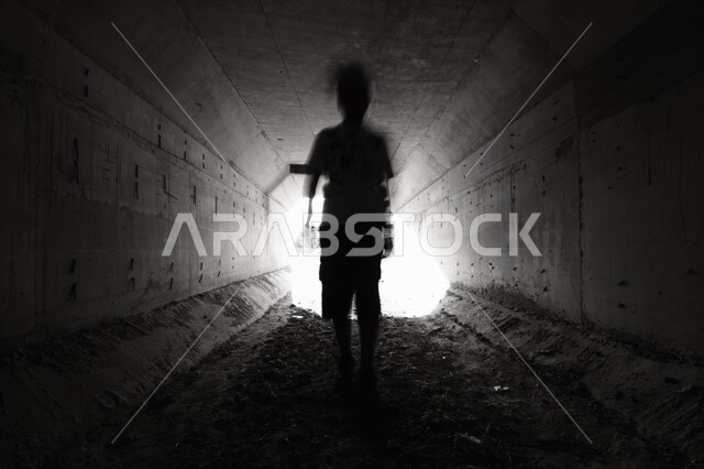 صورة بالاسود والأبيض لولد يقف في داخل غرفه مظلمه, شاب داخل نفق مظلم,  مفهوم الوحده والعزله, التشتت والضياع الفكري في مرحلة المراهقه, هواجس النفس البشريه, سيلوليت، النهاية المشرقة بعد طريق مظلم. 