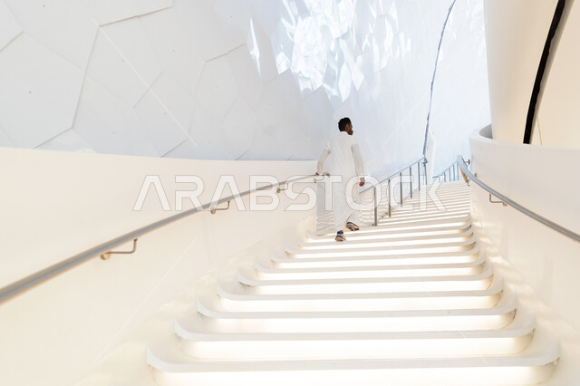 صورة من الداخل لرجل يصعد على درج مركز اثراء المعرفة  في منطقة الظهران في المملكة العربية السعودية ، مركز الملك عبد العزيز الثقافي العالمي ،معارض ومكتبات ، اماكن ثقافية تعليمية في السعودية.