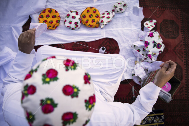 مشروع تطوير الدرعيه التاريخيه, صورة من الاعلى لإمرأة عربية خليجية سعودية تقوم بالتطريز على الاقمشة ,احتفالات افتتاح مطل ومنتزه البجيري في الدرعيه في مدينة الرياض ،معالم تراثية اثرية شعبية مشهورة .