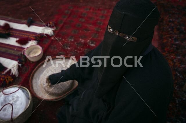 مشروع تطوير الدرعيه التاريخيه, صورة من الاعلى لإمرأة عربية خليجية سعودية ترتدي العباءة السوداء تقوم بتجهيز الاطعمة,احتفالات افتتاح مطل ومنتزه البجيري في الدرعيه في مدينة  الرياض ،معالم تراثية اثرية شعبية مشهورة .