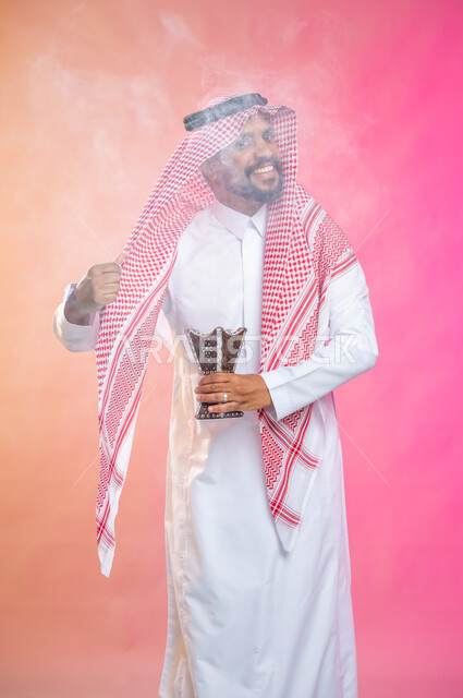 The use of oud wood on occasions and holidays, perfumed with incense and oud, a portrait of a Saudi Arabian Gulf man wearing the traditional Saudi thawb and shemagh, wearing perfume as an incense burner, Saudi customs and traditions, a colored background.