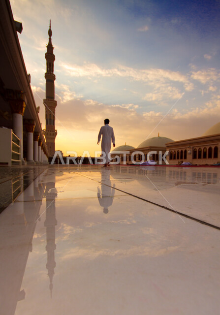 ساحة المسجد النبوي الشريف في المدينة المنورة في المملكة العربية السعودية، العبادة والتقرب إلى الله في أماكن ومعالم دينية إسلامية مقدسة، شارب يرتدي الزي السعودي يمشي في المجمع الخارجي للحرم النبوي الشريف