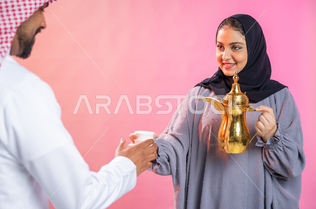 اجواء العائلة السعودية المليئة بالسرور في العيد، بورتريه لإمرأة محجبة تحمل بيدها دلة القهوة العربية, حسن الضيافة والإستقبال و إكرام الضيوف، منتج وطني سعودي محلي، خلفية ملونة.