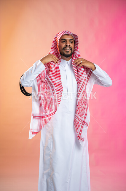 الاهتمام بالمظهر الخارجي و الشياكه و  الأناقة, شاب سعودي عربي خليجي يرتدي الثوب و الشماغ الأحمر, التزين و التجمل و الترتيب, الاستعداد للخروج, خطوات لبس الشماغ السعودي التقليدي, خلفية ملونة.
